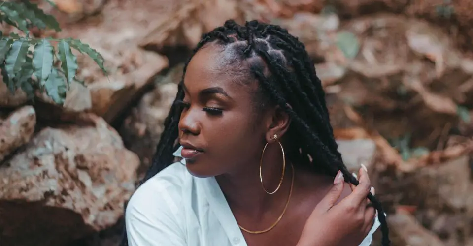 How to Retwist Your Own Locs : a dreadlocked woman sitting among rocks